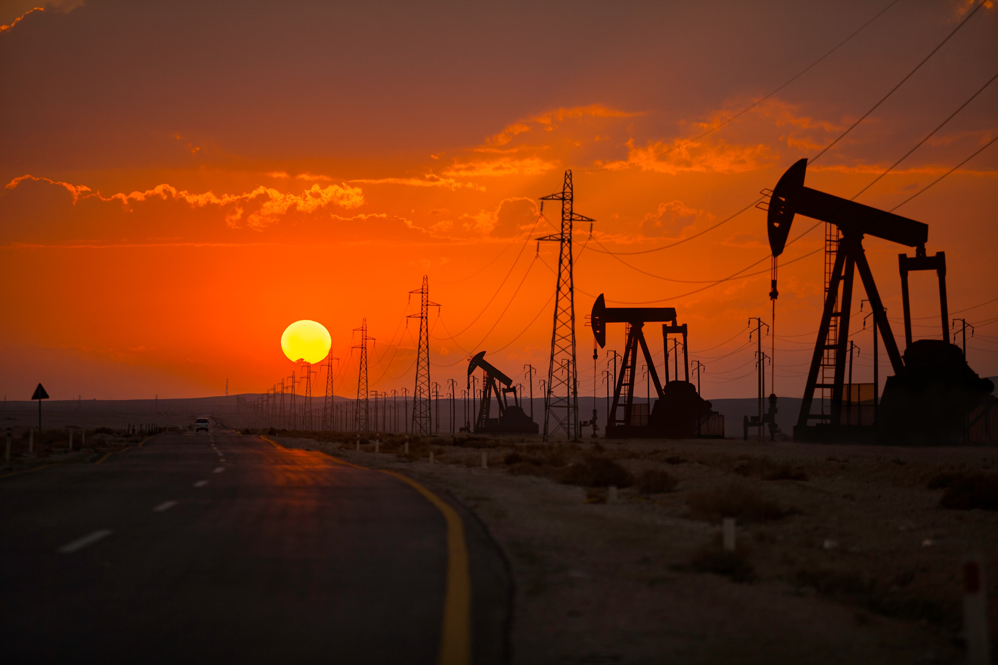 Oil wells and power lines on the side of the highway